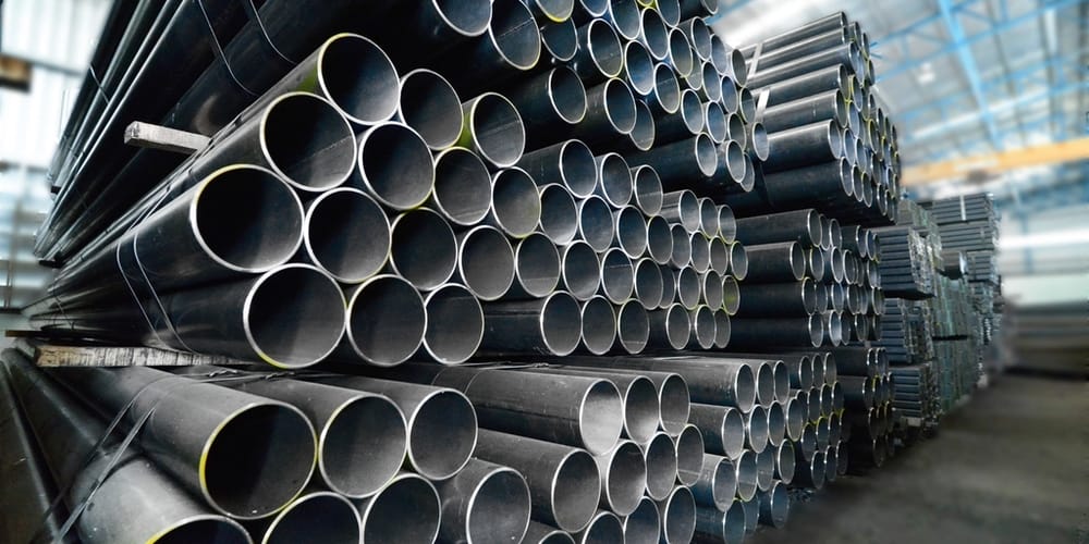 Bundles of steel tube stacked end-on in a warehouse bay, running away in perspective.