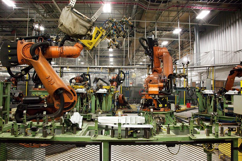 Robotic weld cells on an automotive assembly line, with body panels held in fixtures.