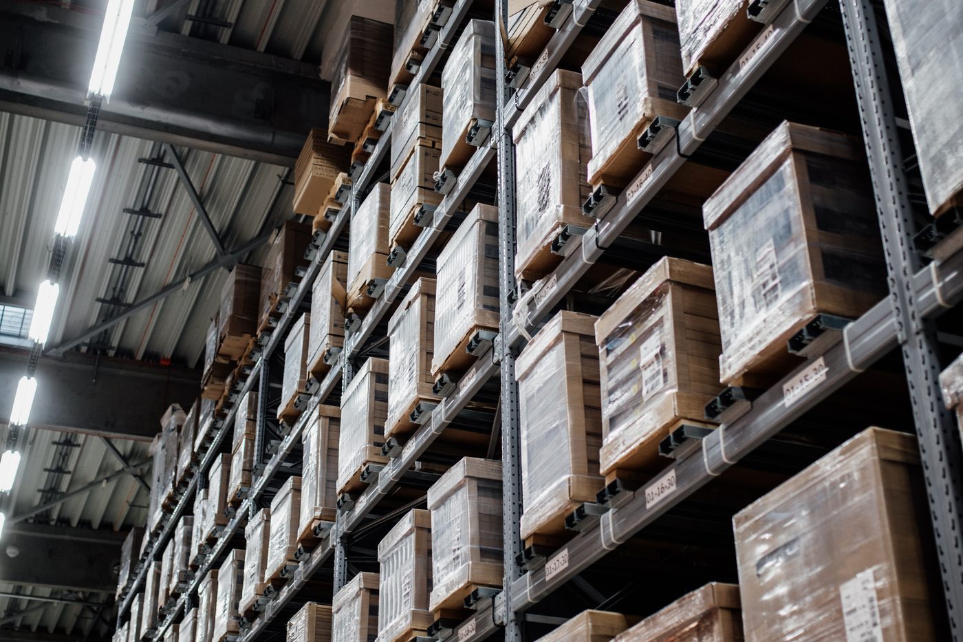 Warehouse racking holding wrapped and labelled stock, each bay marked with a location code.