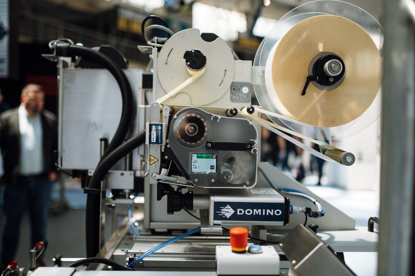 A label applicator on a packaging line, label web and tape reel loaded and running.