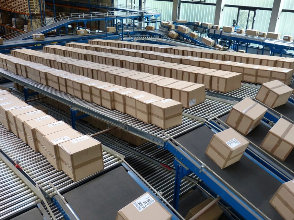 Labelled cartons running down roller conveyor lanes in a sortation hall, routed toward outbound.