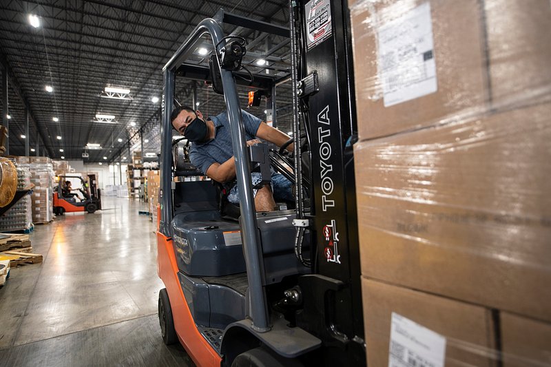 An operator moving wrapped, palletised stock through a distribution facility on a forklift.