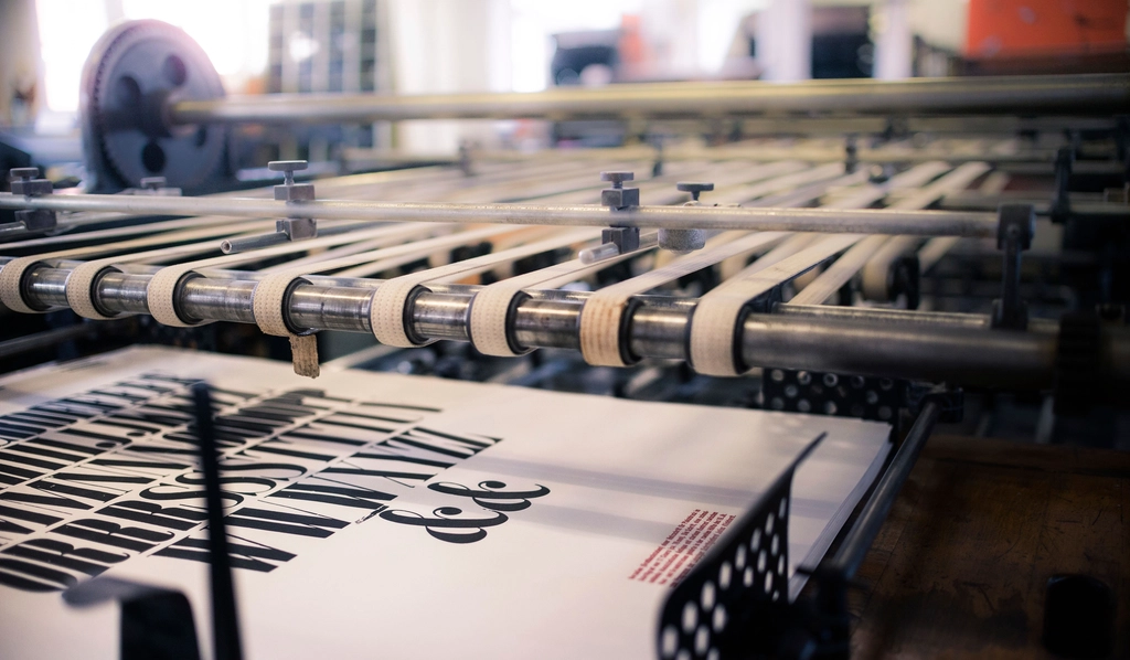 A press line running printed sheet stock through inked rollers.