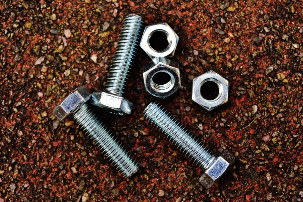 Hex bolts and nuts mixed together, the kind of stock a sort has to separate.