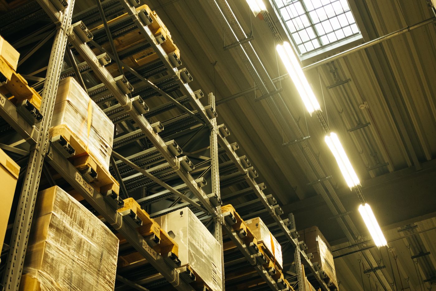 Warehouse racking stacked to the roof with palletised stock, each bay marked with a location code.