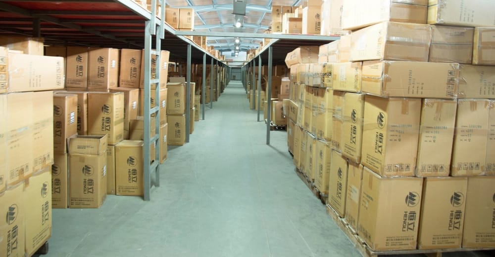 A warehouse aisle stacked with cartons, the warehousing industry page hero.